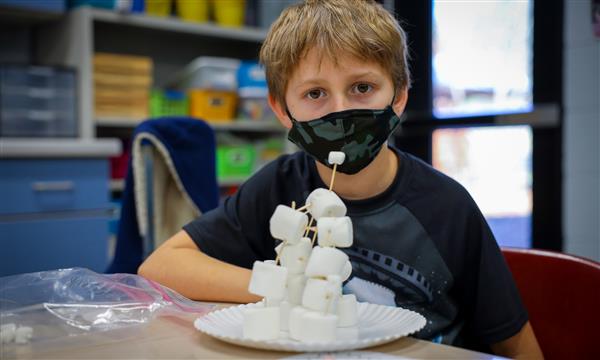 Boy smiles behind his marshmallow tower